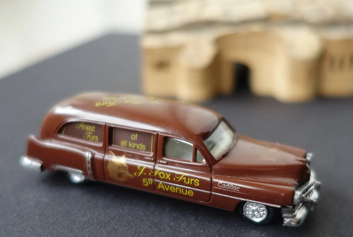 Close-up van een bruine gietijzeren modelauto met gouden opschriften op de zijkant, gefotografeerd op een donkere ondergrond.